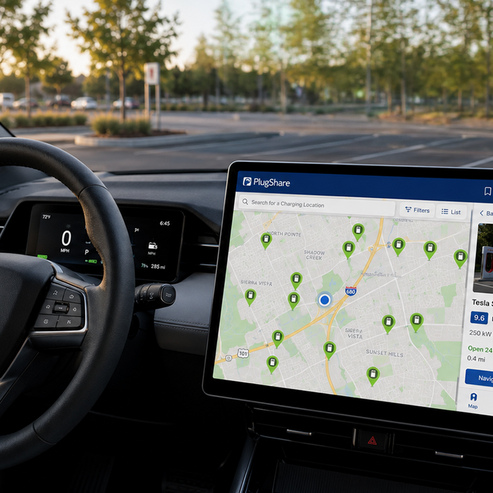 An EV dashboard showing a steering wheel and a large center screen with PlugShare's charging station map.
