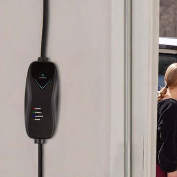 A man plugging a Lectron Level 1 charger into a white Hyundai Ioniq 5 parked outdoors while a young girl looks on.